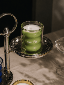Mint and basil scented soy candle in green glass jar on a metal tray