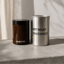 Decorative storage canisters: brown jar (OBJECT 01) and silver cylinder with text