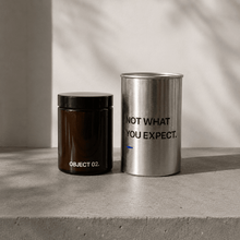 Decorative storage canisters: dark jar (OBJECT 02) and silver cylinder with text