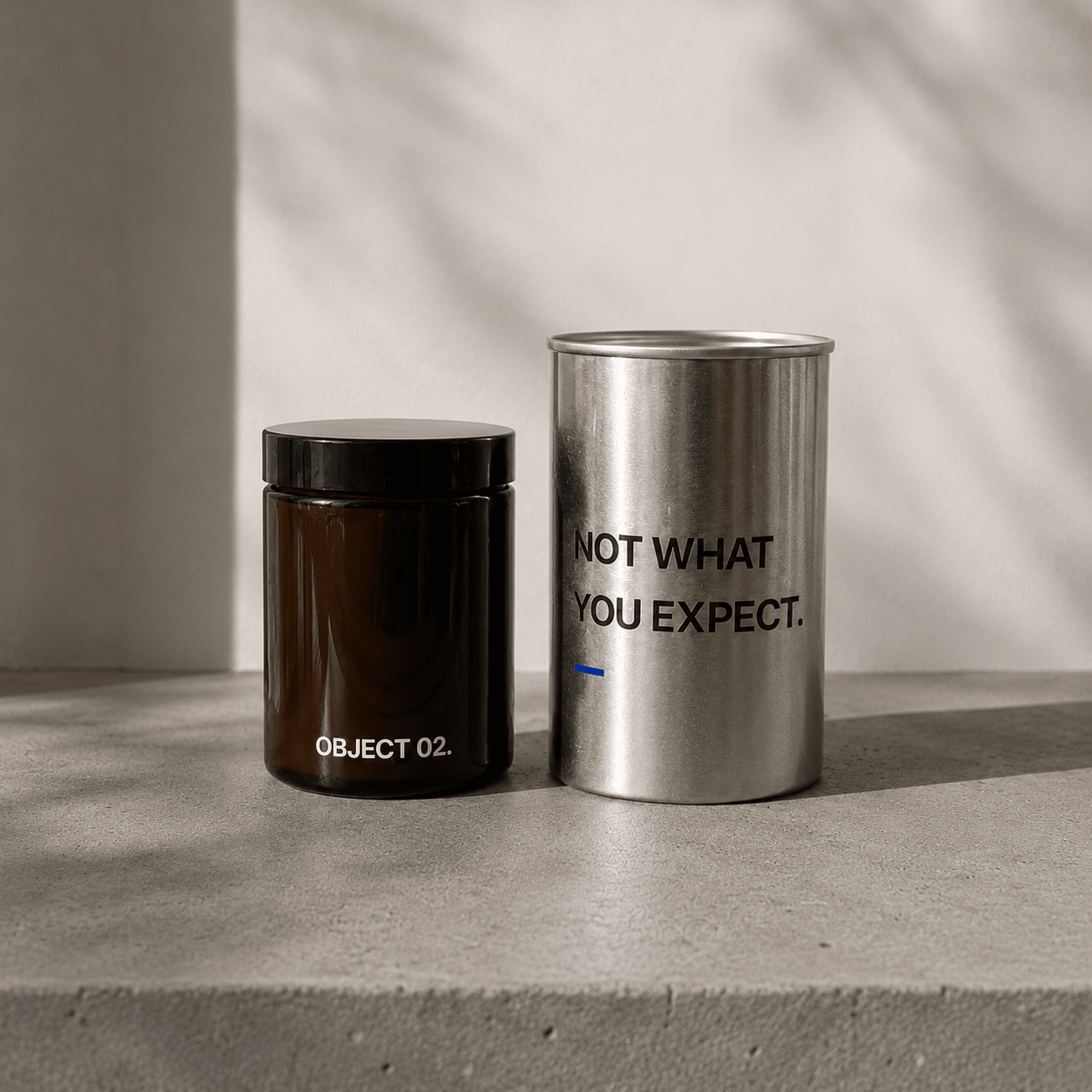 Decorative storage canisters: dark jar (OBJECT 02) and silver cylinder with text