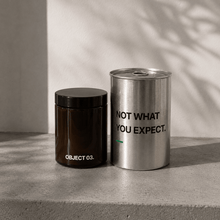 Decorative storage canisters: dark jar (OBJECT 03) and silver cylinder with text