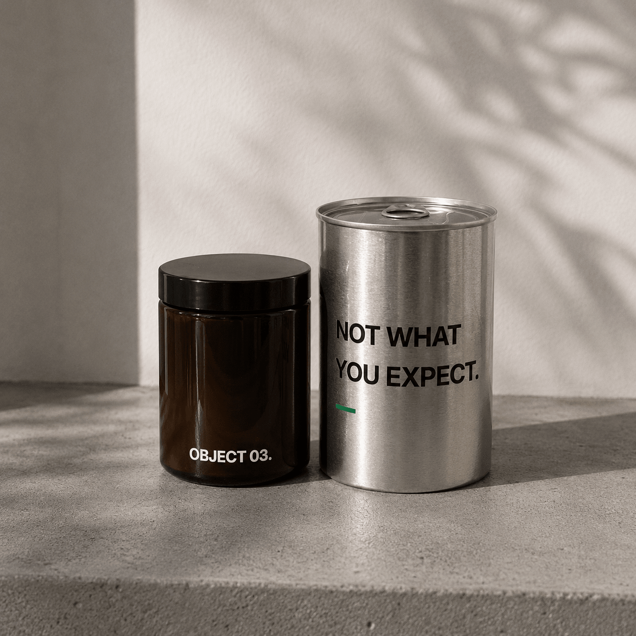 Decorative storage canisters: dark jar (OBJECT 03) and silver cylinder with text