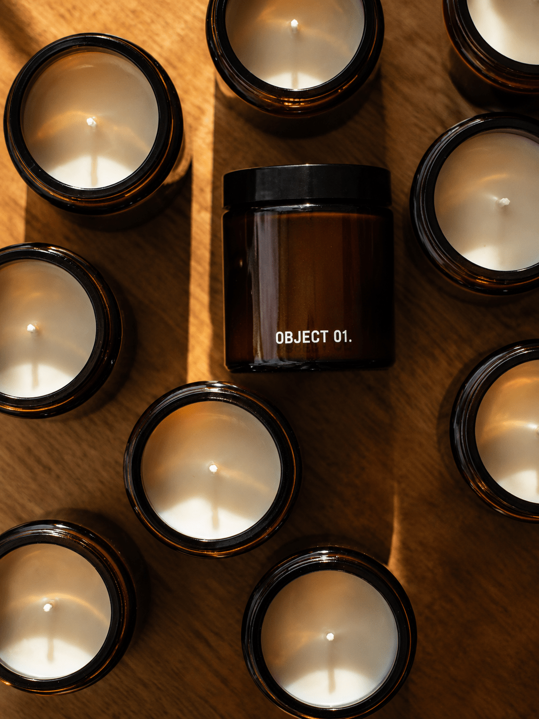 Set of amber glass jar candles with black lids, tops visible and flames in jars