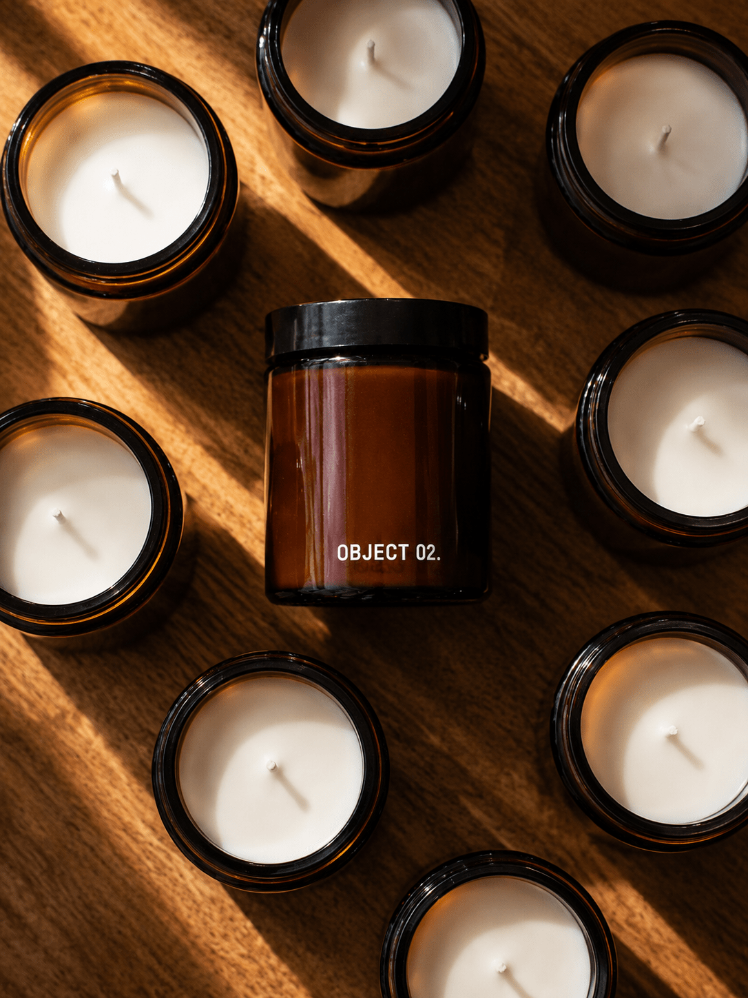 Set of amber glass scented candles with black lids and visible wicks