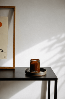 Amber glass scented candle in metal tin, label "OBJECT 03." on a table