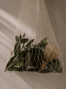 Net-wrapped scented candle with greenery and twine, jar visible under mesh