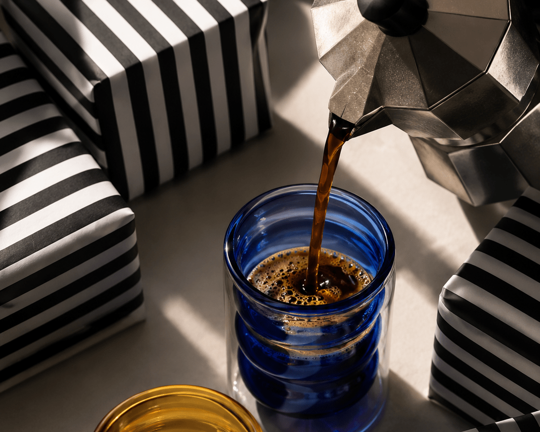 Blue glass candle jar receiving a pour of dark wax, with visible melting surface