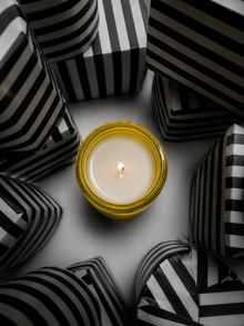 Scented candle in clear glass jar with golden wax and small flame.